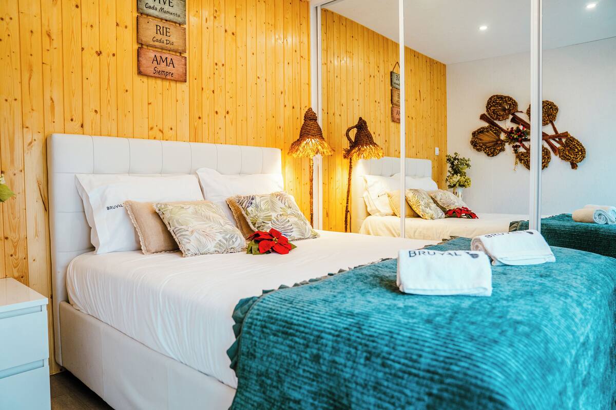 A hotel room with two beds, wooden panel walls, and a large mirror.