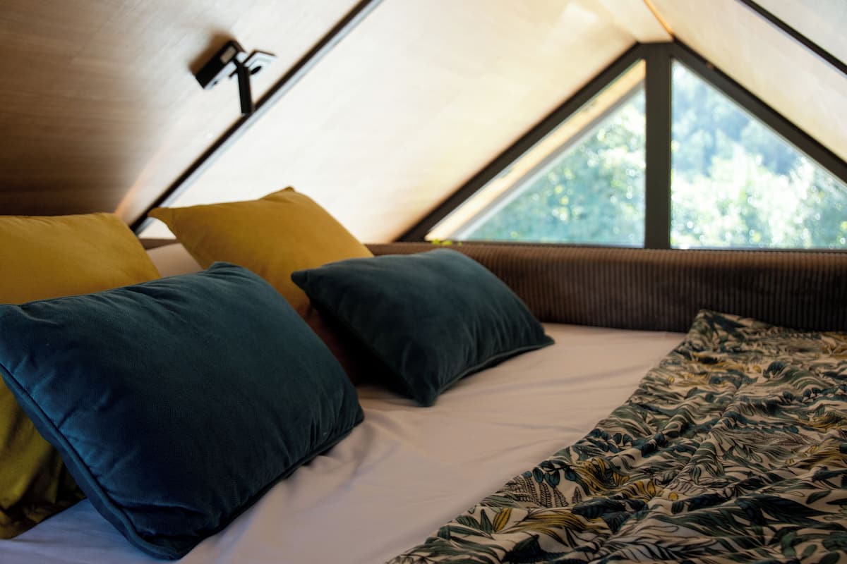 A tent-style bedroom with a bed, pillows, and a patterned blanket.