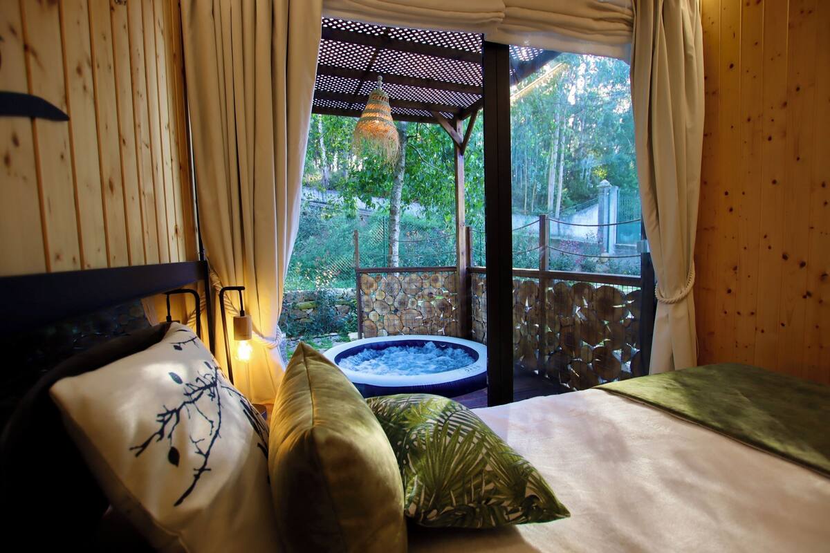 A bedroom with a view of a hot tub and a wooden deck.