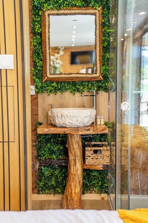 A bathroom with a wooden vanity, a white stone sink, and a mirror framed with greenery. - Bruval Eco Retreat & Eco Village (Vila Nova de Gaia)