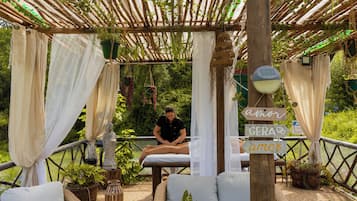 Relax in a serene outdoor oasis with a pergola, cushioned seating, and lush greenery.