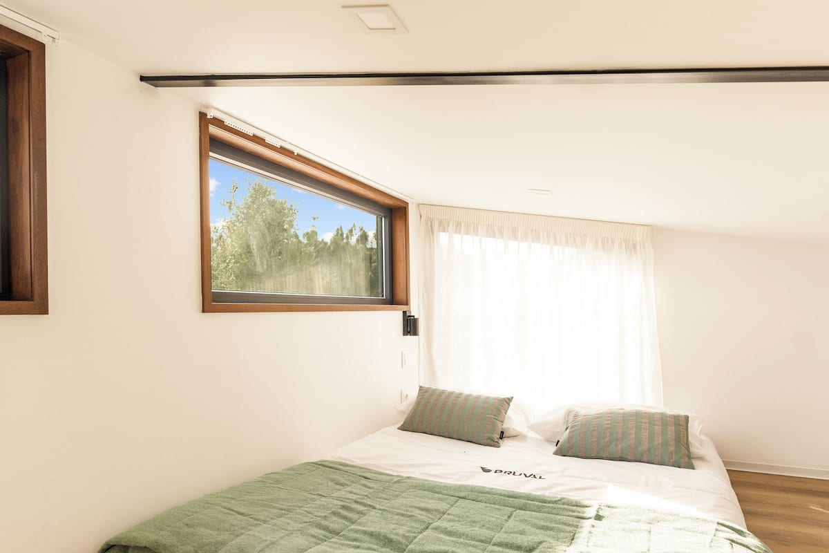 A bedroom with a bed, a window, and a view of trees.