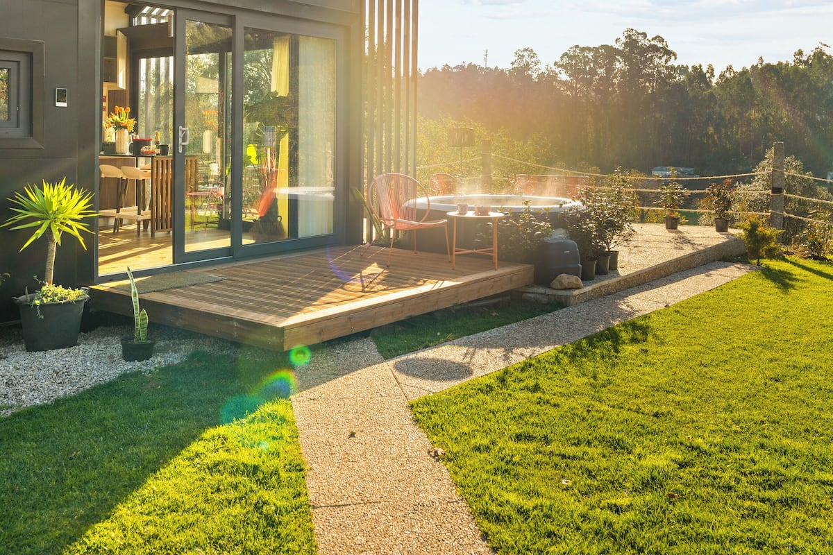 A modern house with a spacious patio, a well-maintained lawn, and a clear view of the surrounding area.