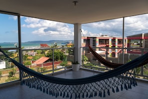 A room with a hammock, large windows, and a view of a beach and buildings. - Villa Nuevo Amanecer Santa Verónica (Juan de Acosta)