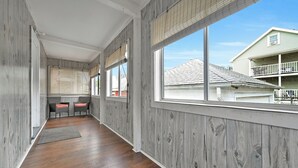Ein langer, schmaler Korridor mit Holzwänden und Holzdielen, der zu einer Sitzecke mit zwei Stühlen und einem Tisch führt.