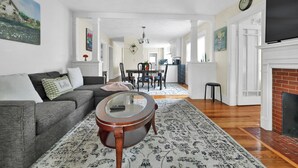 Ein geräumiges Wohnzimmer mit grauem Sofa, rundem Couchtisch und Kamin.