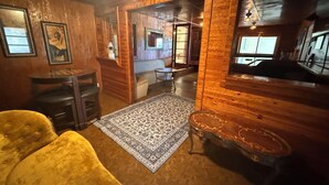 A wooden interior with a sofa, a rug, a small table, and a mirror. - Central 3-bedroom house in Redding with Pool & Vintage Bar Room (Redding)