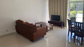 Un salon comprenant un canapé, une table, un téléviseur et un coin repas avec des chaises.