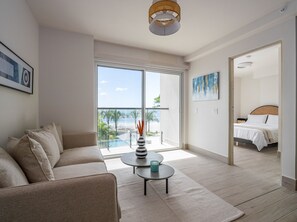 Une chambre d’hôtel moderne dotée d’un balcon, d’un canapé, d’une petite table avec un vase et d’un lit avec une tête de lit.