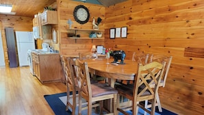 Un intérieur en bois comprenant une table à manger, des chaises et un coin cuisine.