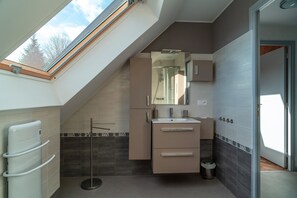 Un baño moderno con tragaluz, ducha integrada y tocador con espejo.