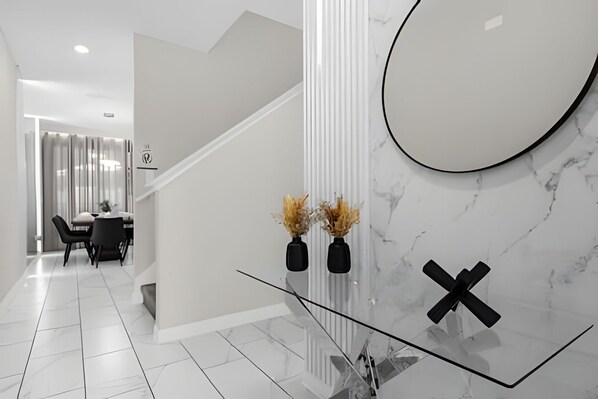 A modern interior with a staircase, a dining area, and a glass table with decorative vases.