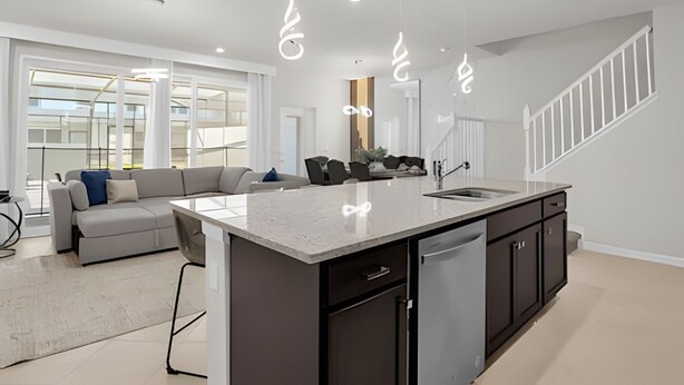 A modern kitchen with a central island, dark cabinetry, and a stainless steel dishwasher.
