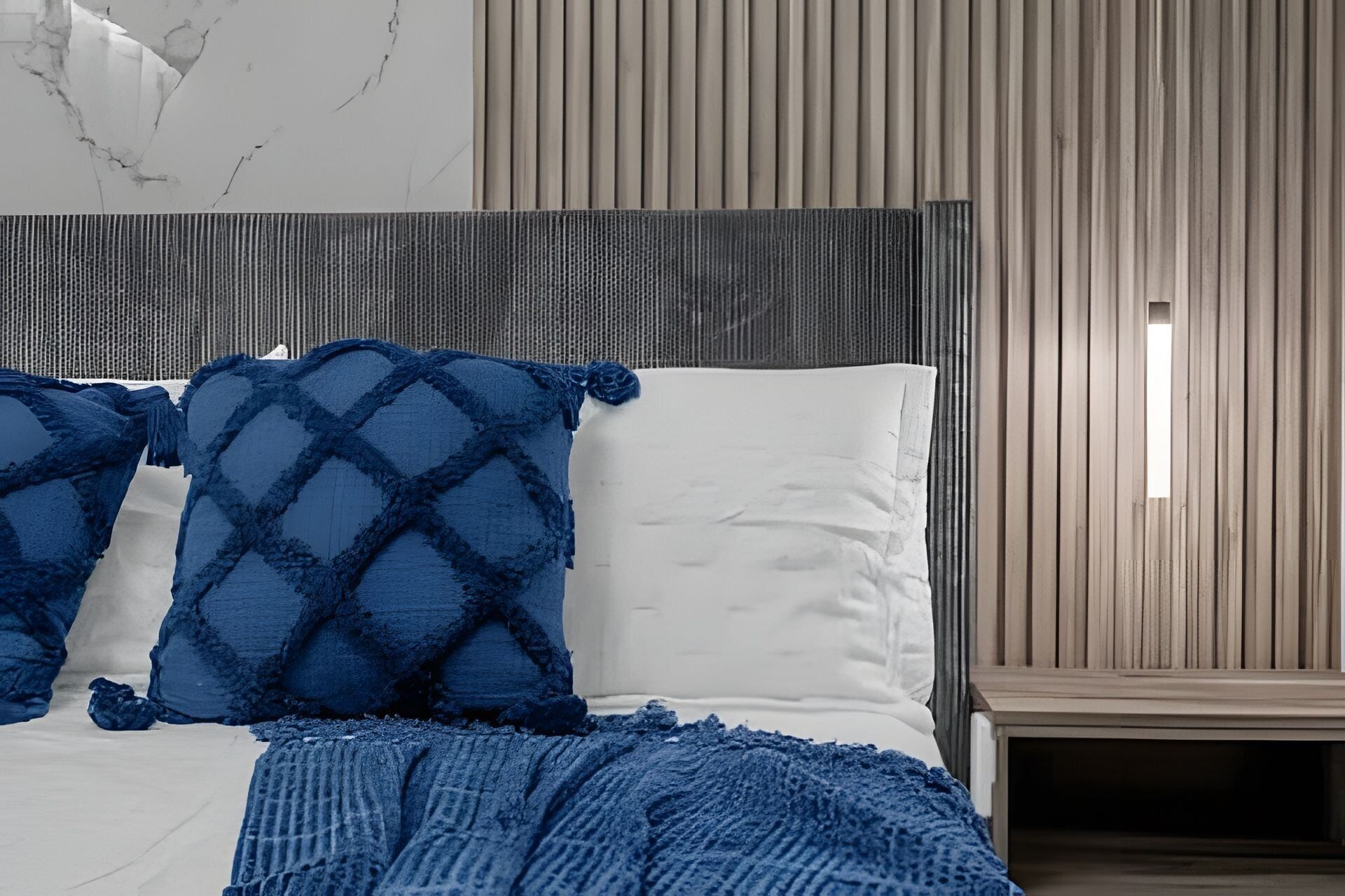 Een bed met witte en blauwe kussens, een blauwe deken en een houten hoofdbord.