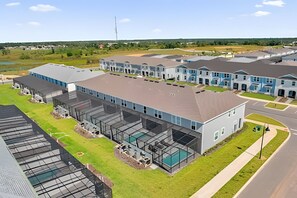Een modern appartementencomplex met meerdere gebouwen, een overdekte parkeerplaats en een zwembad.
