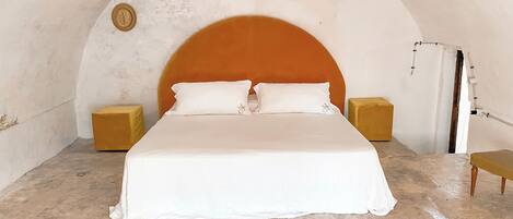 Une chambre à coucher avec un lit, deux tables de chevet, un tapis à motifs zébrés et un plafond en arc de cercle.