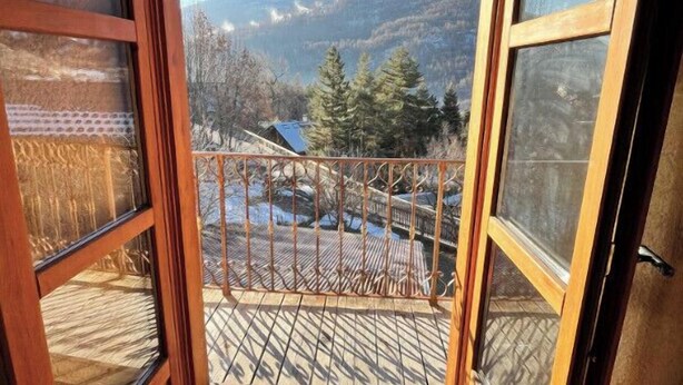 A wooden balcony with a view of mountains and trees.