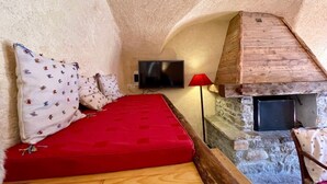 A cozy room with a red sofa, a television, and a stone fireplace.