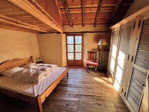 Une chambre à coucher en bois, avec un lit, une chaise, une table et une fenêtre.