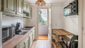 A compact kitchen with a coffee maker, a toaster, and a hanging light fixture.