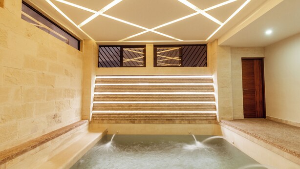 A spa area with a hot tub, geometric ceiling design, and a wooden door. - Xoza Hotel Urban Escape (Cancun)