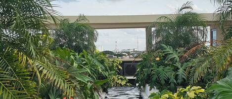 A water feature flanked by lush greenery and a bridge overhead.