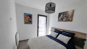 A bedroom with a bed, a window, a radiator, and a wall-mounted artwork.