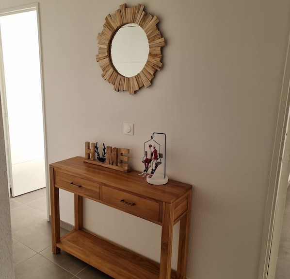 A wooden console table with drawers and a mirror above it.
