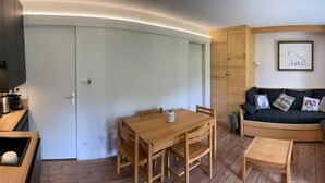 Une pièce chaleureuse avec une table à manger en bois, un canapé et une grande fenêtre.