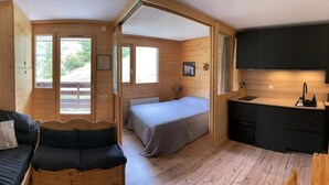 Une cabane en bois avec un lit, un canapé et un coin cuisine.