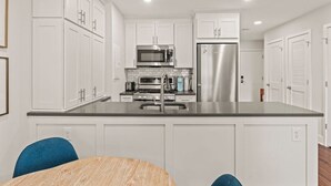 A modern kitchen with white cabinetry, stainless steel appliances, and a central island with a sink. - Washington Square Gem | Patio! (Philadelphia)