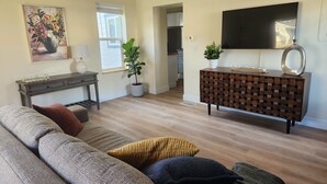 A living room with a sofa, a coffee table, a TV, a console table, and a potted plant.