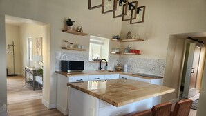A modern kitchen with a central island, white cabinetry, and wooden bar stools.