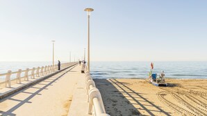 A coastal walkway with a railing, a boat on the beach, and a clear sky. - Casa Liliana Ac Wifi Forte Dei Marmi (Forte dei Marmi)