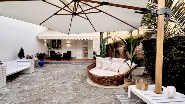 A patio with a wicker swing chair, a white bench, and a table with wooden blocks. - Casa Liliana Ac Wifi Forte Dei Marmi (Forte dei Marmi)