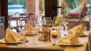 A dining table set with wine glasses, plates, and napkins, with a candle and flowers on the table. - Mobile home with air conditioning, terrace and pool (Santa Lucia/Nuoro)