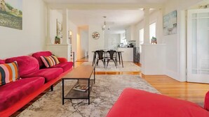 A spacious living area with a red sofa, a wooden coffee table, and a dining area with a table and chairs.