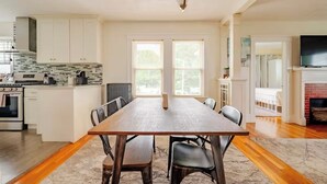 A spacious kitchen with white cabinets, a large island, and a dining area with a wooden table and chairs.