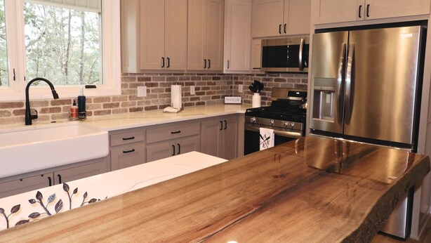 Una cocina moderna con armarios de madera clara, electrodomésticos de acero inoxidable y encimera de madera.