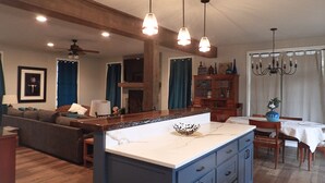 Una cocina amplia con una isla grande, armarios de madera e iluminación colgante.