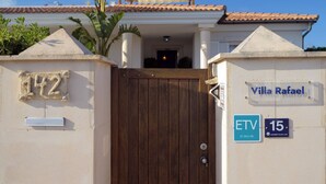A gated villa with a wooden door, a nameplate reading "Villa Rafael," and a street number sign "142." - Charming spacious villa, 200 m from the sea, swimming pool, garden, AC, wifi... (Marina de Son Ganxo)