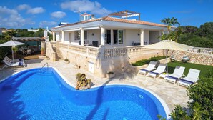 A villa with a swimming pool, outdoor seating, and a stone pathway. - Charming spacious villa, 200 m from the sea, swimming pool, garden, AC, wifi... (Marina de Son Ganxo)