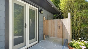 A residential property with a sliding glass door entrance, a wooden fence, and a potted plant with flowers.
