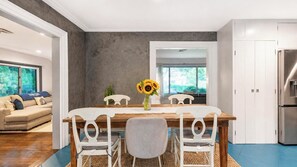 A dining area with a wooden table, white chairs, and a vase of sunflowers.