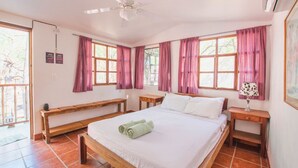 Ein Schlafzimmer mit einem Bett, zwei Nachttischen, einer Bank und einem Deckenventilator.