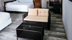 A modern hotel room with a bed, a sofa, a small table, and a wooden door. - Africa Waka Waka (Lungi)