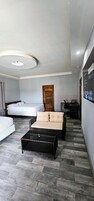 Una habitación de hotel moderna con una cama, un sofá, una mesita y una puerta de madera.