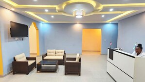 A reception area with a reception desk, a flat-screen TV mounted on the wall, and a seating area with sofas and a coffee table. - Africa Waka Waka (Lungi)