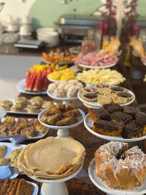 A buffet with various food items including pancakes, pastries, and desserts. - Pousada Pura Vida (Itacaré)