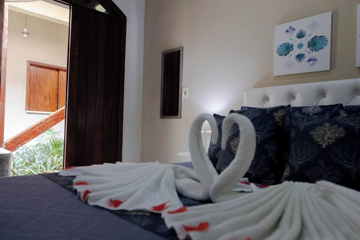 A hotel room with a bed, a window, and a door.